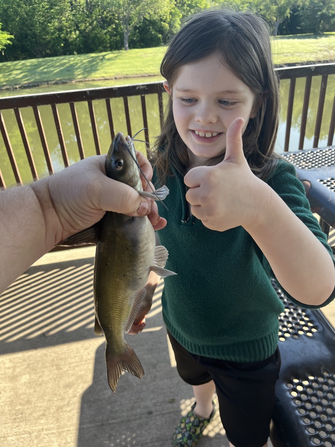 Jack smiling while holding a fish beside the water
